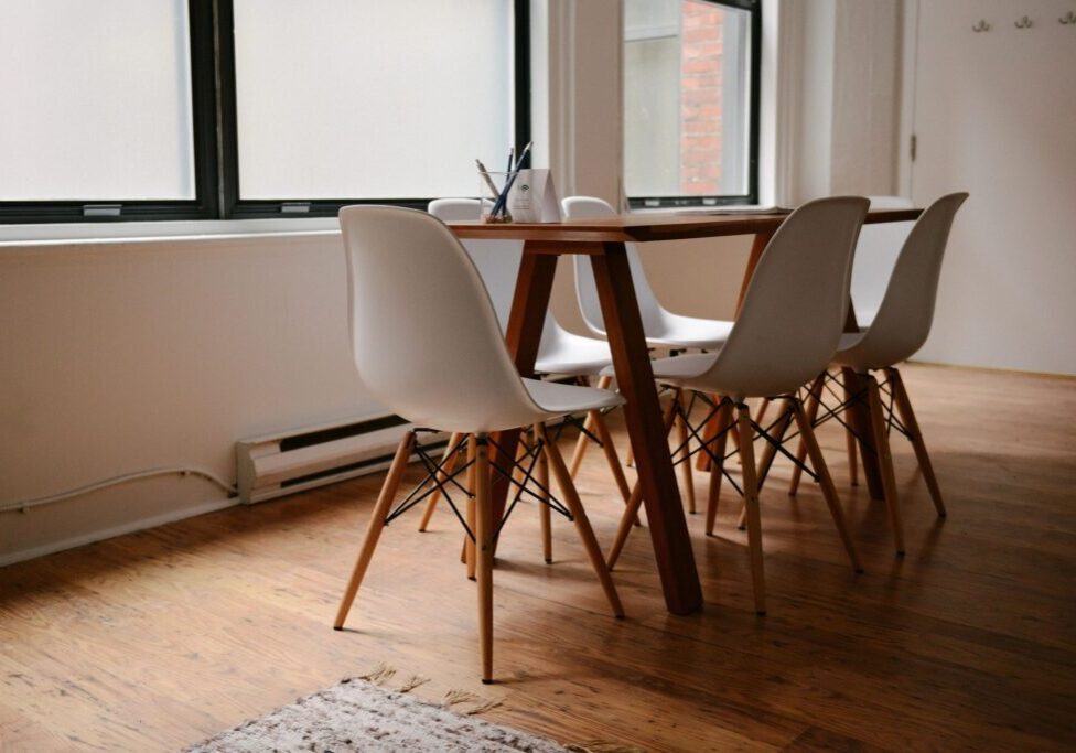 A table and chairs in front of windows.